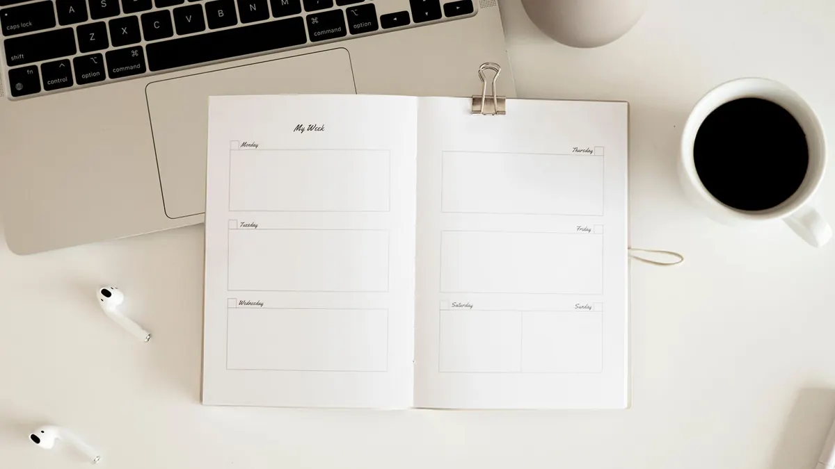 Open minimalist planner beside a laptop and coffee