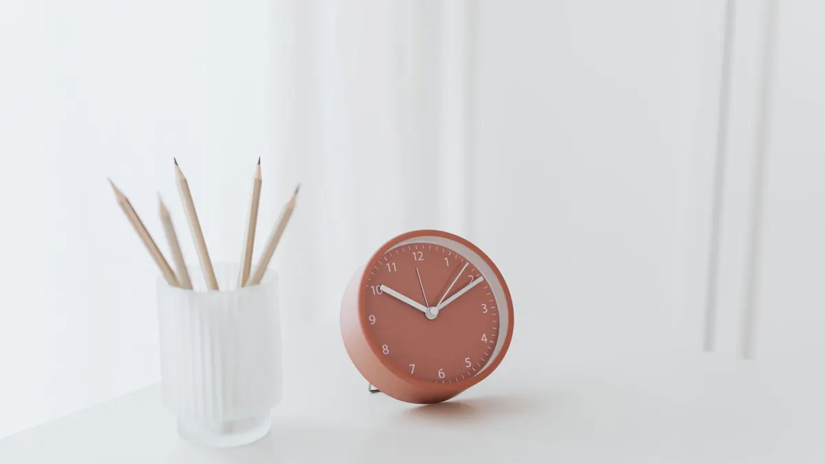 Small clock and pencils on a bright minimal desk