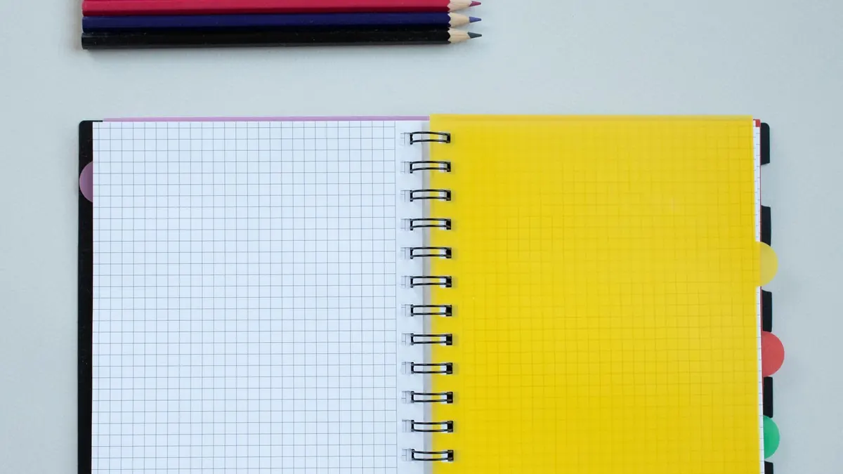 Colored pencils beside a yellow spiral notebook