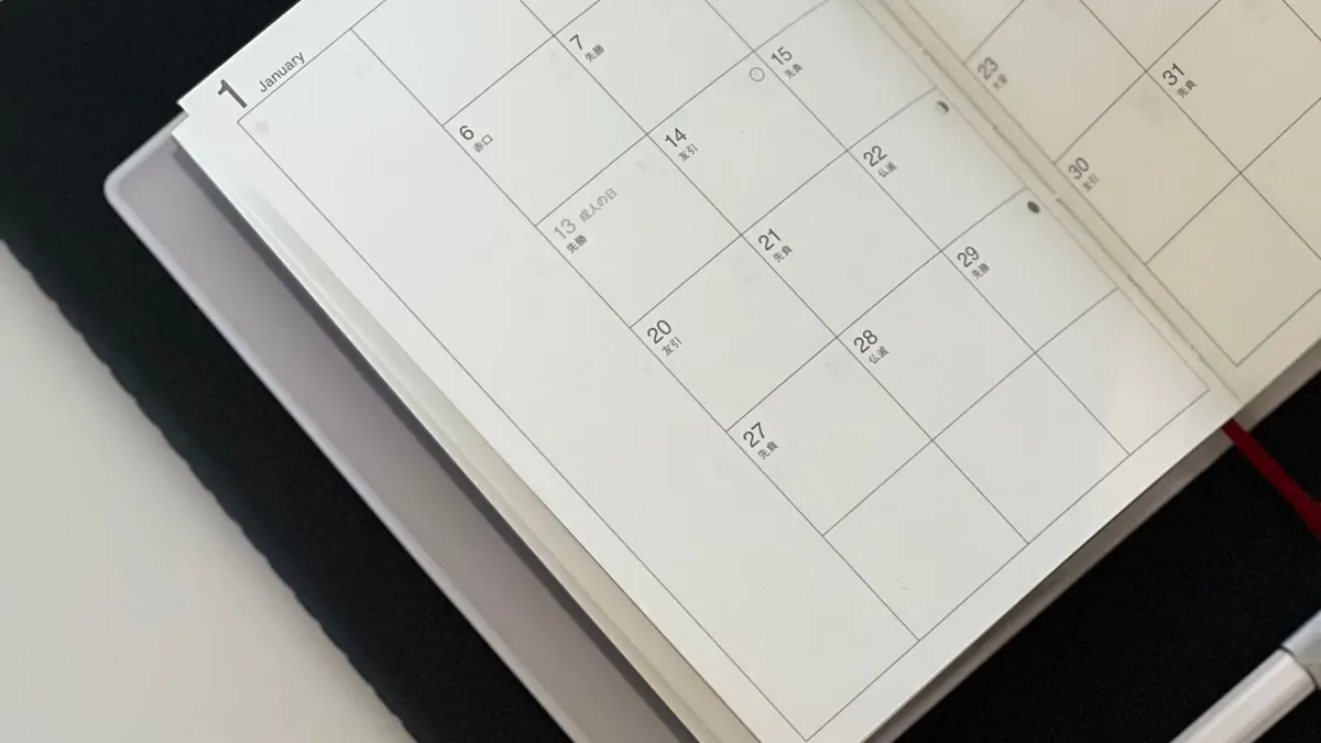 Open paper calendar with a pen on a dark desk